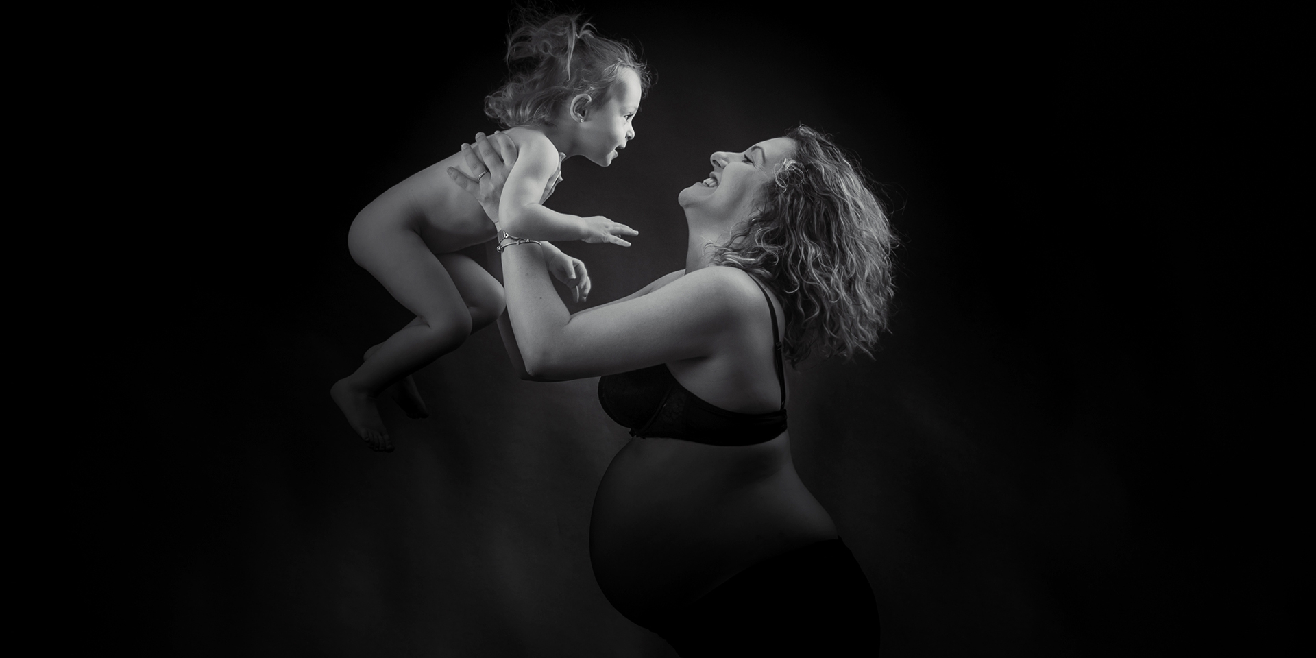 Pose dans le mouvement d'un maman et son enfant en studio en noir en blanc.