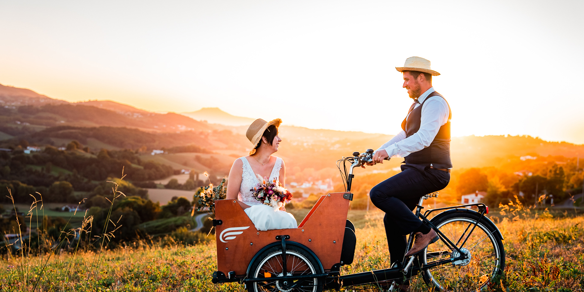 Un soir au coucher du soleil, un couple de mariés dans un triporteur dans un champ.
