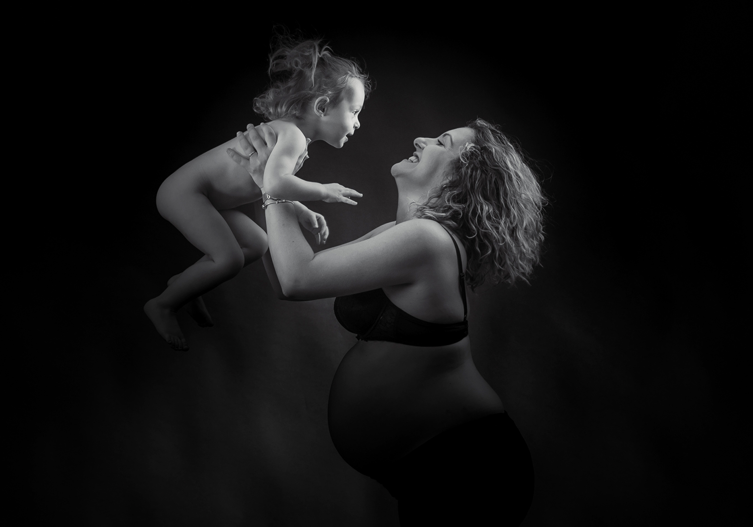 Pose dans le mouvement d'un maman et son enfant en studio en noir en blanc.